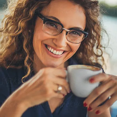 Cincinnati Dental Services. Woman smiling at camera holding a cup